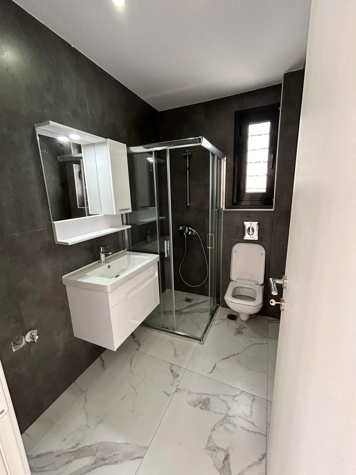 Bathroom with black tile and marble surfaces